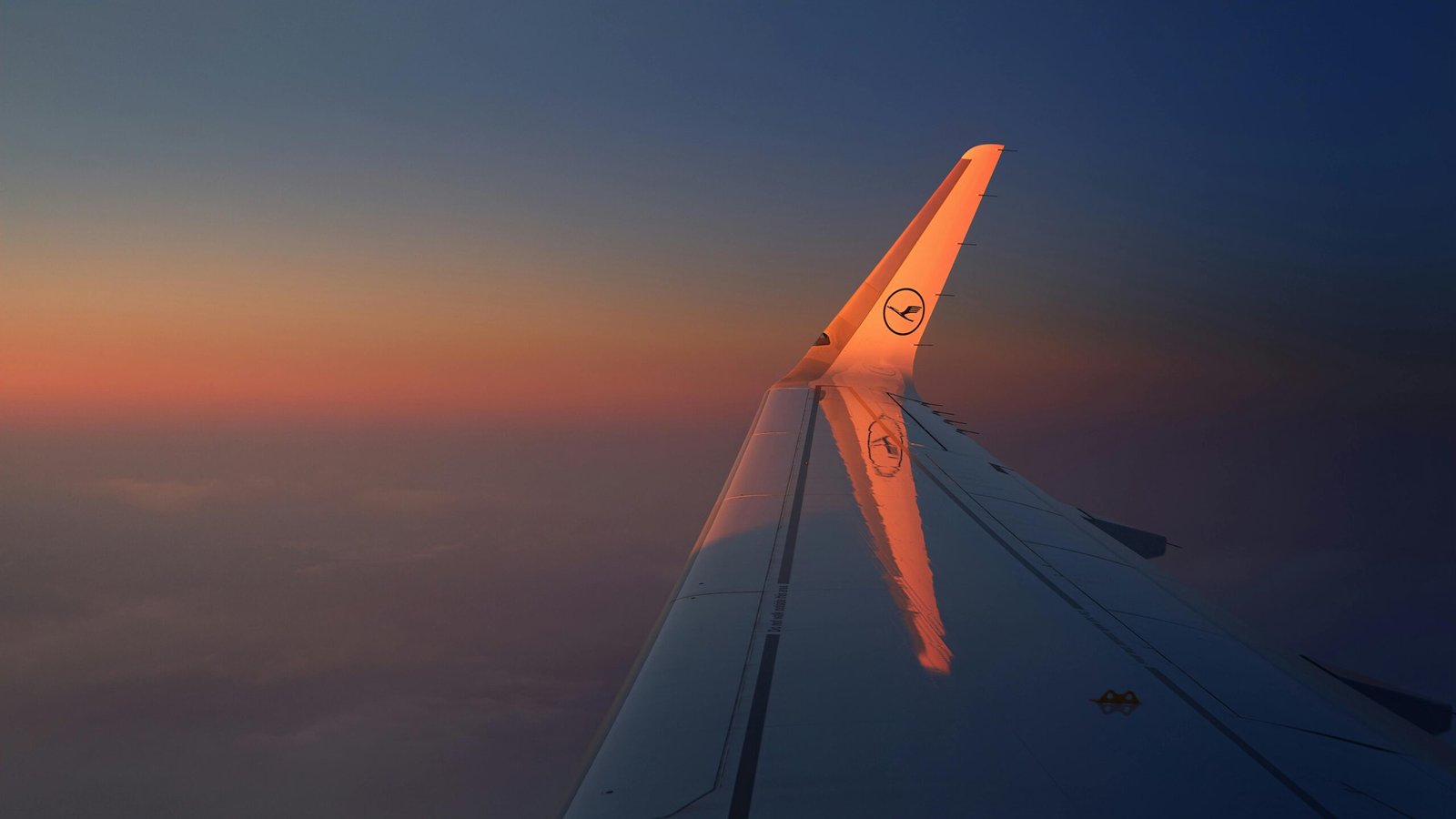 Capture the serene beauty of an airplane wing against a vivid sunset sky, perfect for travel enthusiasts.